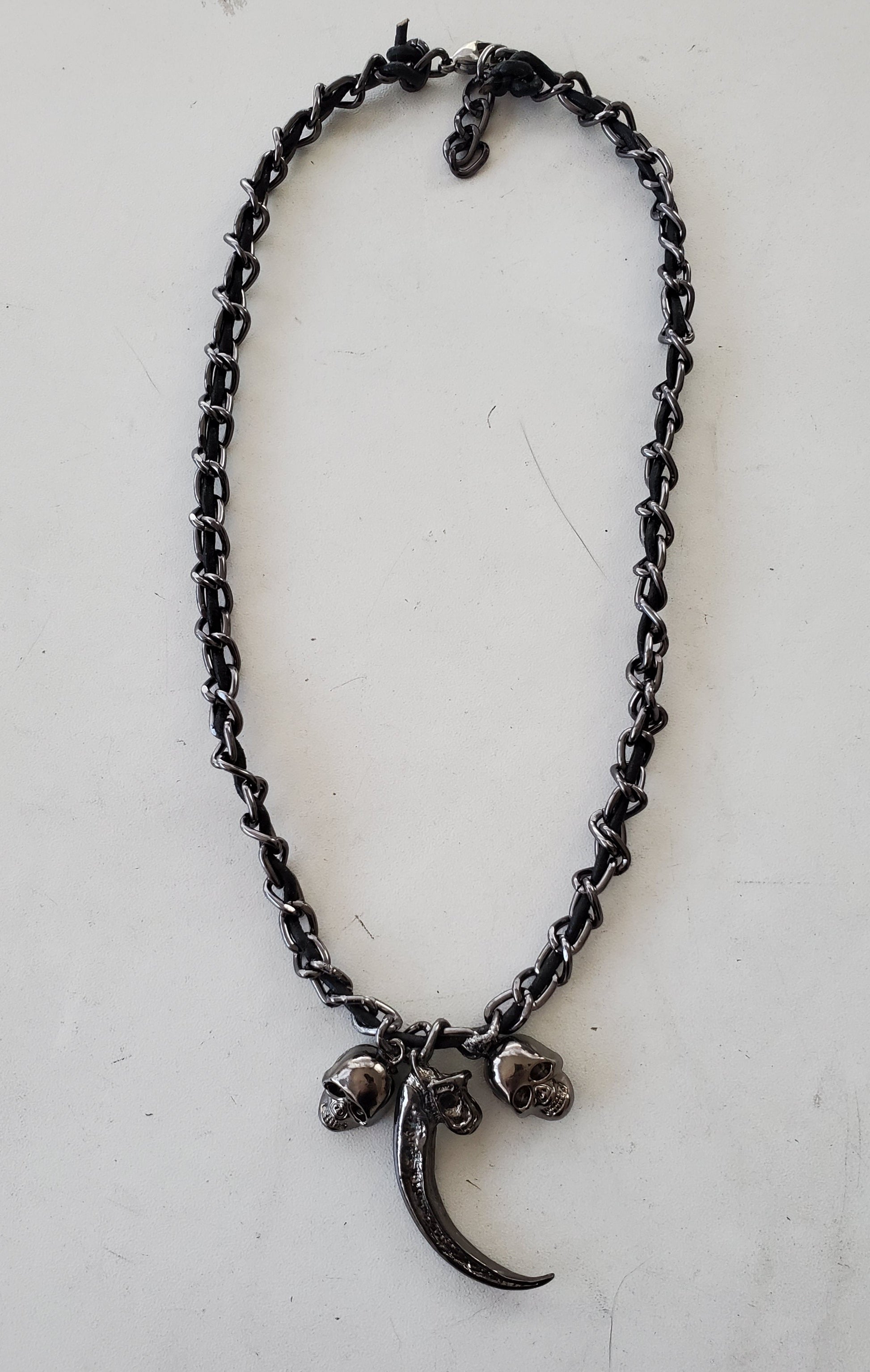 Black chain necklace with a crescent moon and skull pendant on a white background