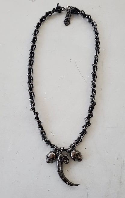 Black chain necklace with a crescent moon and skull pendant on a white background